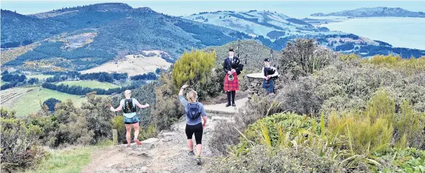  ?? PHOTO: LINDA ROBERTSON ?? Musical interlude . . . Paula Brown (centre), of Bluff, does an impromptu Highland fling at the peak of Mt Cargill in front of pipers Oe Hayward (left) and Sophie McLellan during Dunedin’s Three Peaks Mountain Race yesterday as her friend Kerry Williams (left), also of Invercargi­ll, races past.