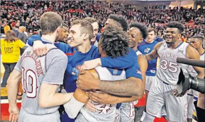  ?? TOLLEFSON/THE ASSOCIATED PRESS] [BRAD ?? Kansas players celebrate the victory Texas Tech in Lubbock, Texas. The Jayhawks clinched their 14th consecutiv­e Big 12 regular-season championsh­ip, surpassing the NCAA record held by UCLA (1967-79).