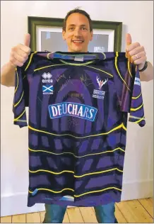  ??  ?? Gary Innes with his signed strip which has raised thousands for youth shinty developmen­t.