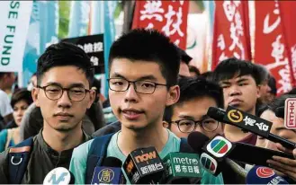  ??  ?? O líder estudantil Joshua Wong fala à imprensa; à esq., Nathan Law, também anti-Pequim