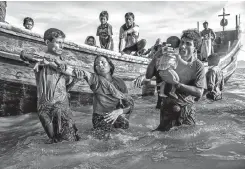  ??  ?? A Rohingya refugee woman is helped from a boat as she arrives exhausted on the Bangladesh side of the Naf River, at Shah Porir Dwip, after fleeing from her village in Myanmar.