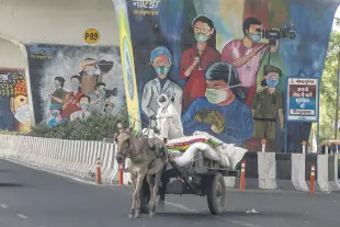  ??  ?? A man rides a horse cart past a mural depicting frontline workers in Noida, a suburb of New Delhi, India, April 15, 2021.