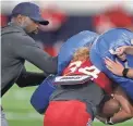  ??  ?? UA first-year running backs coach DeMarco Murray whacks running back John Burton with a pad during practice last week.