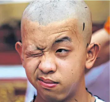  ??  ?? Pornchai Kamluang and his team-mates having their heads shaved in a Buddhist ceremony in Mae Sai district, Chiang Rai province