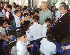  ??  ?? UDA beramah mesra dengan murid yang menerima bantuan di SK Tansau, Putatan.