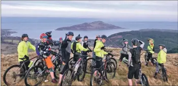  ??  ?? Members of the club stop for a quick group photo on a trail overlookin­g Holy Isle.