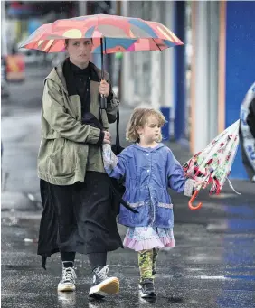  ?? PHOTOS: GERARD O’BRIEN ?? Rosie and Madeline (5) Trist, of Dunedin, cross Frederick St in the rain yesterday afternoon.