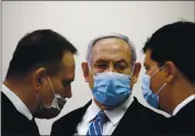  ?? RONEN ZVULUN — POOL PHOTO VIA AP ?? Israeli Prime Minister Benjamin Netanyahu, center, looks at his lawyer inside the courtroom as his corruption trial opens at the Jerusalem District Court on Sunday.