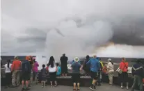  ??  ?? Visitors watch as steam and gas rise Wednesday from Kilauea’s summit crater in Volcanoes National Park, Hawaii. Geologists warn that the volcano could erupt explosivel­y and send boulders, rocks and ash into the air around its summit in the coming weeks.