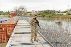  ?? CHENEY ORR/THE NEW YORK TIMES ?? A member of the U.S. National Guard patrols Tuesday on top of shipping containers used to keep migrants out of the United States along the Rio Grande in Shelby Park in Eagle Pass, Texas.