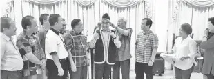  ??  ?? Manyin (fifth right) puts the Bidayuh traditiona­l headgear on Westmorela­nd (middle). Also in the photo are Dr Jerip (third right) and (from left) Dr Sinang, Henry, Ik Pahon and Ranum.