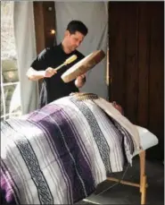  ?? SUBMITTED PHOTO ?? Marie Cooney’s son, Sean, offers visitors to her Holistic Health Fair a Shamanic Reiki treatment believed to impart “healing energy” to the recipient. The drum used is believed to create a spiritual vibration as well as a relaxing beat. According to...