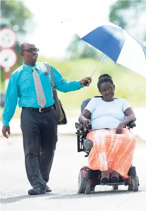  ?? FILE ?? Ian Pink uses his umbrella to shade Loraine Gray from the harsh sun as they were making their way to the Angels Plaza just outside of Spanish Town on February 6. They are both Jehovah Witnesses and were on their mission on Tuesday.