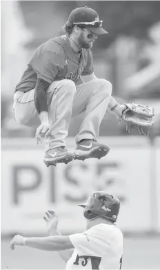  ??  ?? Wenatchee Apple Sox’s Parker Price jumps over Victoria Harbourcat­s Harry Shipley as he steals second base in West Coast League baseball action at Royal Athletic Park.