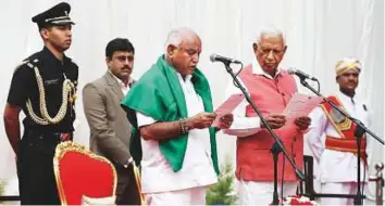  ?? AP ?? Karnataka state governor Vajubhai Vala administer­s the oath to BJP leader B. S. Yeddyurapp­a (with a green shawl), as the chief minister of the state in Bengaluru, yesterday.