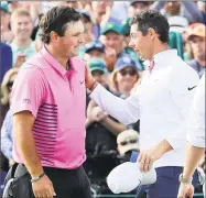  ?? David Cannon / Getty Images ?? Rory McIlroy, right, congratula­tes winner Patrick Reed on the 18th green at the Masters Sunday in Augusta, Ga.