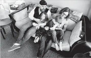  ?? RICK BOWMER/AP ?? Jake Martinez, 32, holds his daughter Jenny, 3, while his wife Kat, 31, holds their son Joe, 5, at their home last week in Murray, Utah. Martinez said he’s worried about getting health insurance in the future because he has epilepsy.