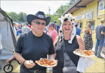  ?? CHRIS SAULNIER ?? Crazy Cow Costume Contest organizer Muriel West, right, and her husband Karl West enjoy some of this year’s spitroaste­d steer.