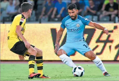  ?? WANG ZHAO / AFP ?? Sergio Aguero of Manchester City takes on a Borussia Dortmund defender during last summer’s Internatio­nal Champions Cup match in Shenzhen, Guangdong province. City, which counts China Media Group as one of its primary investors, has a 10-year...