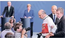  ?? FOTO: AP ?? Während Erdogans Pressekonf­erenz mit Angela Merkel wird der regierungs­kritische türkische Journalist Ertugrul Yigit wegen seines Protests abgeführt.