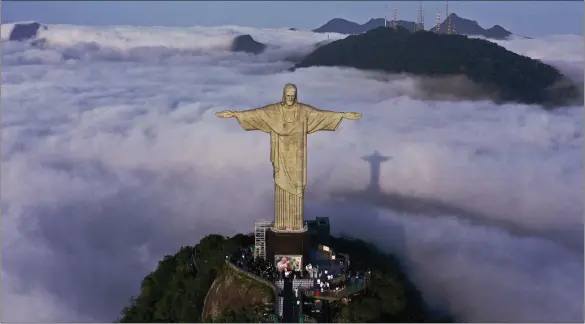  ?? ?? Brazilian landmark Christ The Redeemer, standing almost 100ft high, is reflected in the mist as it towers above Rio de Janeiro and marks 91 years since its constructi­on