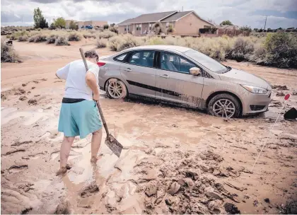  ?? ROBERTO E. ROSALES/JOURNAL ?? Susan Lang helps dig out a car stuck in mud near Cow Court and Alberta Avenue in Rio Rancho. In the 17 years Lang has lived in the area, Thursday night’s downpour was the worst she has experience­d.