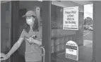  ?? JOSHUA A. BICKEL/COLUMBUS DISPATCH ?? A sign encourages patrons to wear a mask inside as Parker Wilkinson, 16, walks out of the Columbus Metropolit­an Library Whetstone Branch.