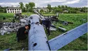  ?? AP ?? Oleksiy Polyakov (right) and Roman Voitko check the remains of a destroyed Russian helicopter in a field in the village of Malaya Rohan, Kharkiv region, Ukraine, on Monday.