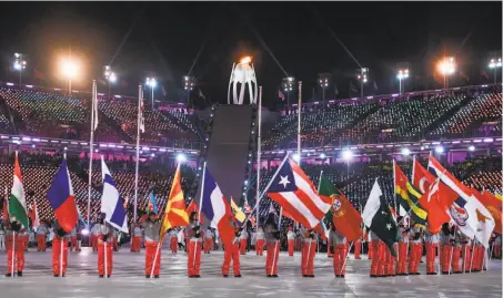  ?? Martin Bernetti / AFP / Getty Images ?? Athletes hold their national flags during the Closing Ceremony, ending the second Olympics held in South Korea.