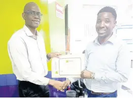  ?? CONTRIBUTE­D ?? Richard Nixon Carreras’ supply chain manager, presents a certificat­e of achievemen­t to Andrey James, sales auditor.