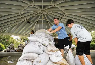  ?? CHIP SOMODEVILL­A / GETTY IMAGES ?? Boy Scout volunteer Thomas Lewis, 12, and his father, Jay, of La Grange, North Carolina, help stack sandbags donated by the city of Greenville at the Farmers Market on Sunday in Kinston, North Carolina.