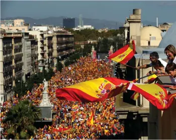  ?? (Photo by Manu Fernandez, AP) ?? People on a rooftop wave Spanish flags during a march in downtown Barcelona, Spain, to protest the Catalan government’s push for secession from the rest of Spain, Sunday Oct. 8, 2017. Sunday’s rally comes a week after separatist leaders of the Catalan...