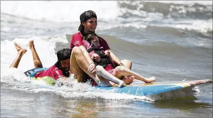  ?? PHOTOS BY COURTNEY SACCO / CORPUS CHRISTI CALLER-TIMES ?? Volunteers help Lucia Martinez of San Antonio go surfing Saturday during the “They Will Surf Again” event at the Horace Caldwell Pier in Port Aransas. Hundreds of volunteers were on hand for the free adaptive surfing event.