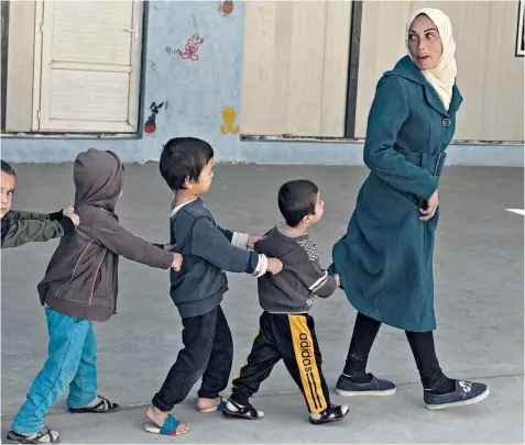  ?? ?? Annoud, whose husband died fighting for SDF forces against Islamic State in 2017, leads exercises at the Helat Centre, where children living in prison go to learn