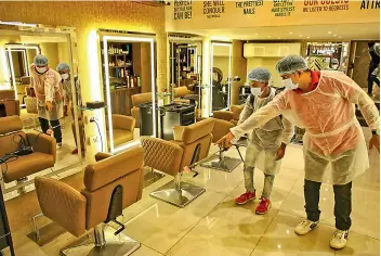  ?? PTI ?? Workers sanitise a salon ahead of its reopening after government announced easing of restrictio­ns, in Mumbai on Sunday. —