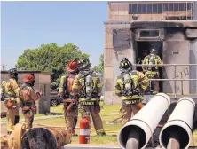  ?? SOURCE: BRYAN, TEXAS, FIRE DEPARTMENT ?? Firefighte­rs stand outside the Bryan, Texas, Utilities Power Plant after an explosion and fire that injured Earle Robinson, 60, and other employees, Robinson died of his injuries a few days later.