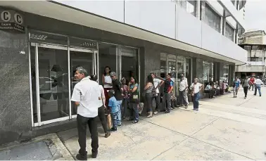  ??  ?? Hard times: People queuing outside a bank in Caracas in the hope of withdrawin­g money. — AP