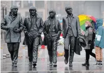  ?? JON SUPER THE ASSOCIATED PRESS ?? People wear masks Monday near a statue of The Beatles in Liverpool, England, a city that’s seen one of the country’s most severe outbreaks, with about 600 cases per 100,000 people.