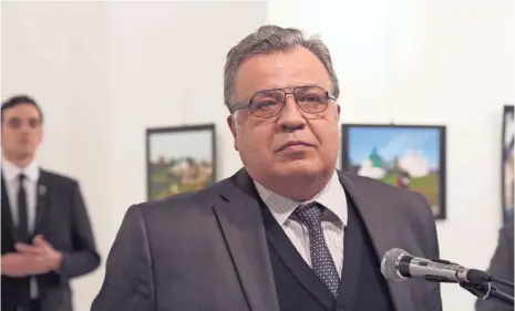  ?? PHOTOS BY BURHAN OZBILICI, AP ?? The Russian ambassador to Turkey, Andrei Karlov, speaks at gallery in Ankara on Monday, moments before a gunman, rear left, shot him multiple times, killing him. The gunman, a Turkish police officer, was fatally shot by special forces.