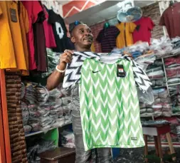  ?? AFP ?? A man displays Nigeria World Cup jerseys at the Balogun Market in Lagos on Thursday. The Super Eagles jersey for the 2018 World Cup in Russia has been hugely popular, both domestical­ly and internatio­nally, with fans scrambling to get their hands on the...