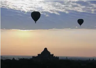  ?? Esther Htusan photos / Associated Press ?? Hot-air balloons carry tourists at sunrise above the ancient Myanmar city of Bagan. The flights are a popular tourist activity in Bagan, home to the world’s largest concentrat­ion of Buddhist temples.