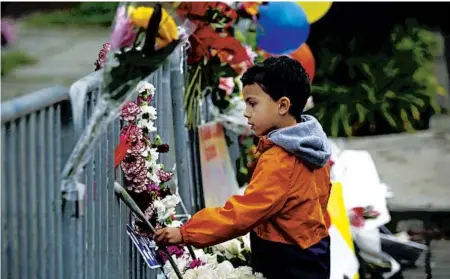  ?? FRANCINE ORR/LOS ANGELES TIMES ?? Titus Cromwell, 4, places a flower from his family’s home in Oakland near the scene of the Ghost Ship warehouse.