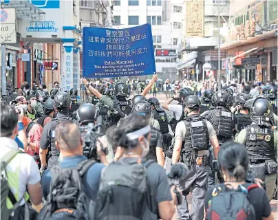  ??  ?? WARNING: Police hold up a banner as protesters take to the streets in Hong Kong over delays to elections