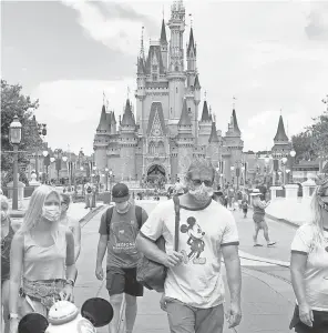  ??  ?? Guests wear masks to attend the official reopening of the Magic Kingdom at Walt Disney World in Lake Buena Vista, Fla., on July 11. JOE BURBANK/ AP