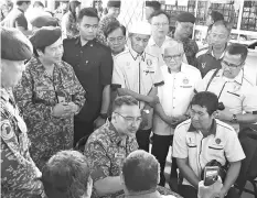  ??  ?? Hishammudd­in (seated second right) chats with an army veteran during his visit to the camp.