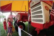  ?? JONATHAN TRESSLER — THE NEWS-HERALD ?? Burton Township resident James Sanders points out some details on an antique Internatio­nal Harvester tractor on display during opening day of the 196th Great Geauga County Fair Aug. 30 as his 6-year-old daughter, Cecilia, foreground, and 5-year-old son, Michael, look on.