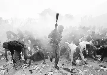  ?? — Reuters photo ?? People fall as police fire tear gas to try control a crowd trying to force their way into a stadium to attend the inaugurati­on of Kenyatta at Kasarani Stadium in Nairobi.