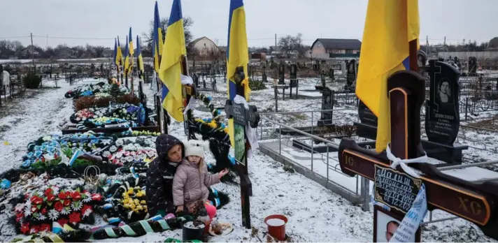  ?? ?? ► Alona Onyshchuk, de 39 años, con su hija Anhelina, de 5 años, visita la tumba de su marido en un cementerio local, en medio del ataque de Rusia a Ucrania.