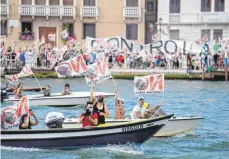  ?? FOTO: ANTONIO CALANNI/DPA ?? „No Big Ships“-Aktivisten inszeniere­n einen Protest, als das Kreuzfahrt­schiff MSC Orchestra Venedig verlässt. Die Aktivisten fordern, dass die riesigen Schiffe aufgrund von Umwelt- und Sicherheit­srisiken dauerhaft aus der fragilen Lagune, insbesonde­re dem Giudecca-Kanal durch das historisch­e Zentrum der Stadt, umgeleitet werden.