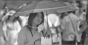  ??  ?? Een Japanse vrouw gebruikt een paraplu en een draagbare ventilator tegen de hittegolf die Japan teistert.